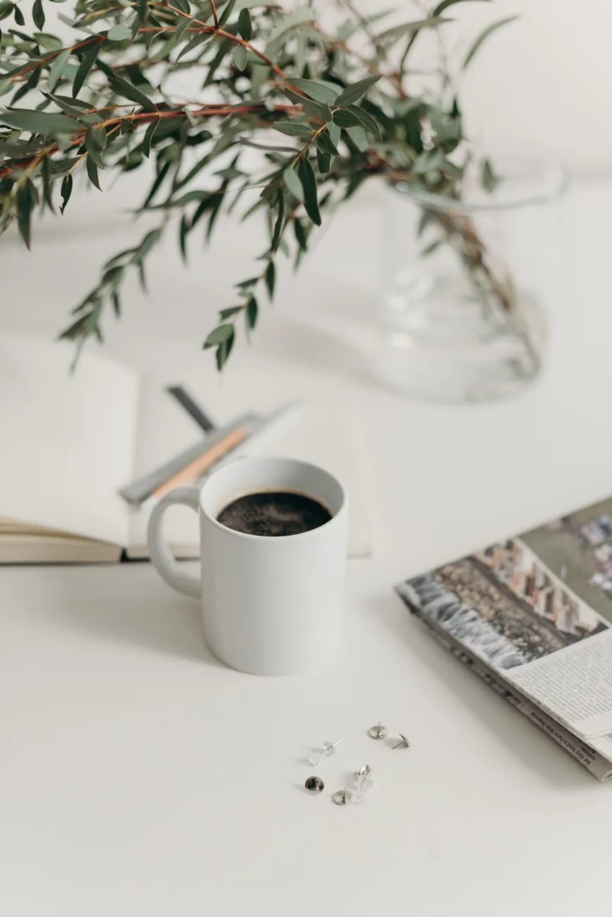 Taza de café junto a una libreta de seguimiento de hábitos y una balanza de cocina